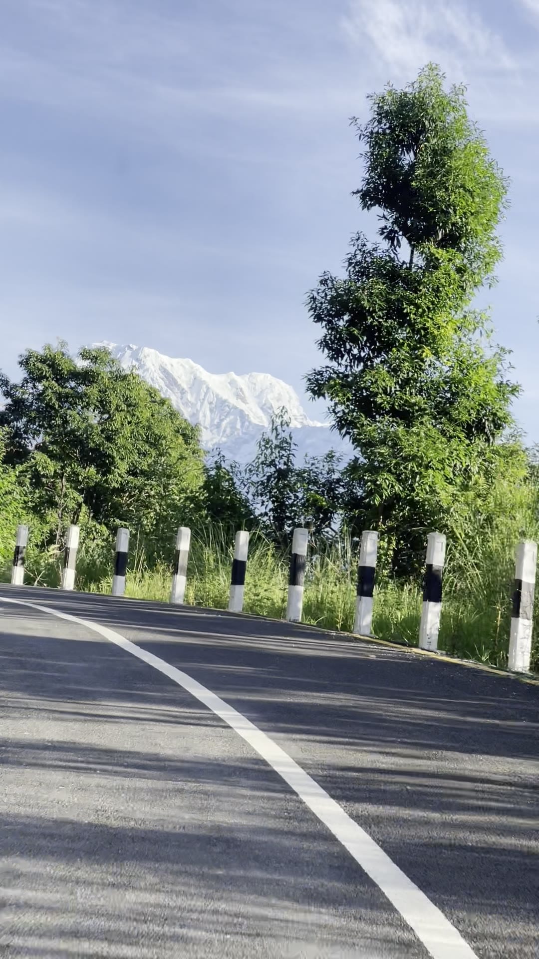 The road climbing toward the resort, marker posts along its edge and snow peaks ahead.